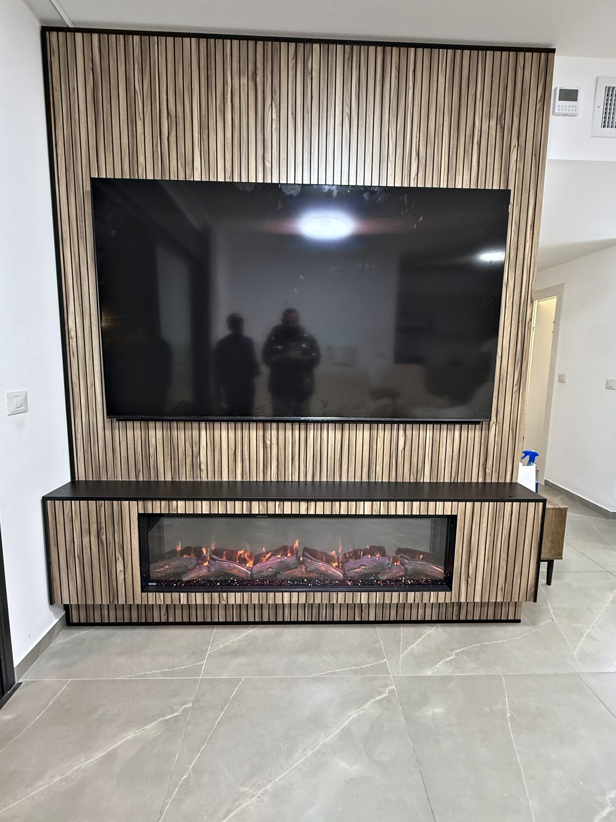 קמין חשמלי עם מסגרת במזנון עם פסי עץ – עבודה של Frenkel Walls