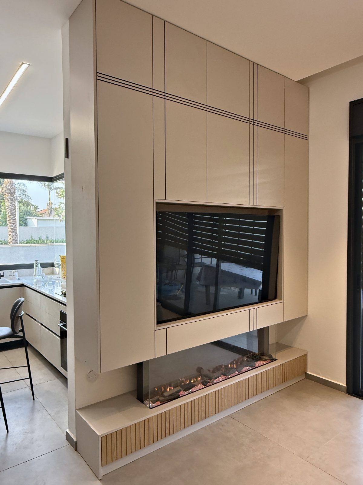 קמין חשמלי פינתי מתחת לטלוויזיה בקיר מפריד – עבודה של Frenkel Walls