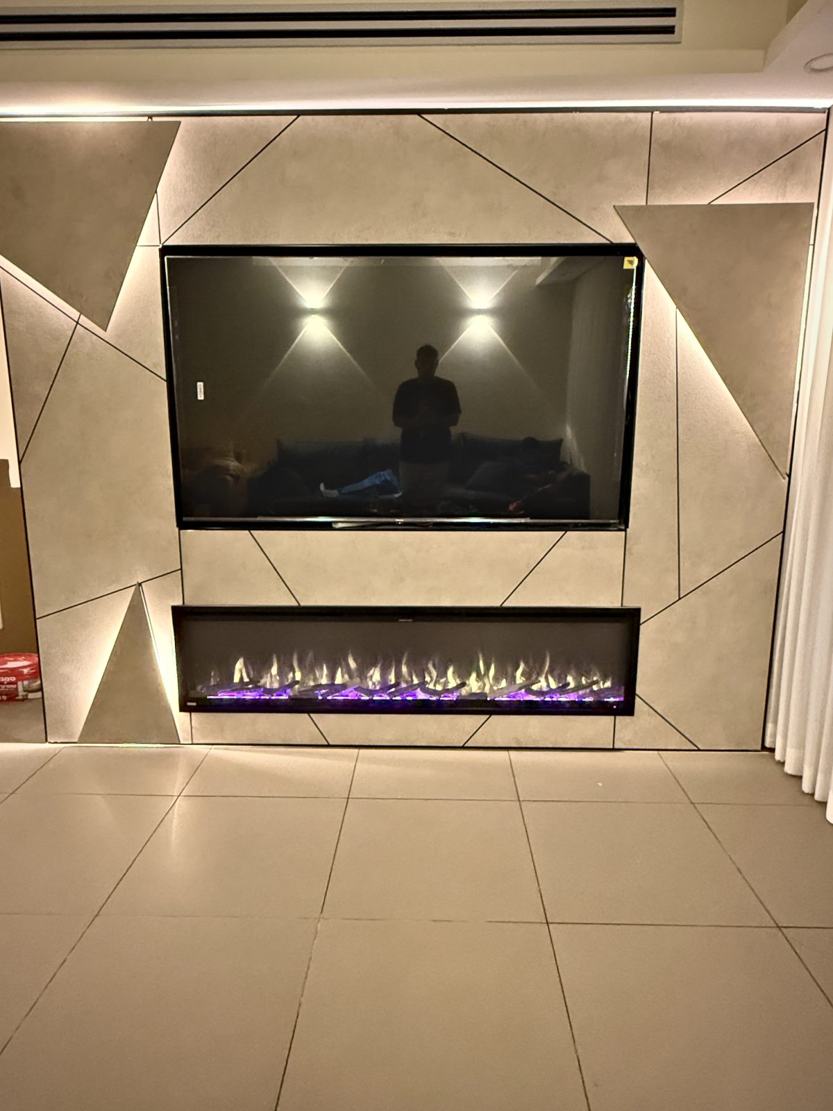 קמין חשמלי צר מתחת למסך בקיר גיאומטרי